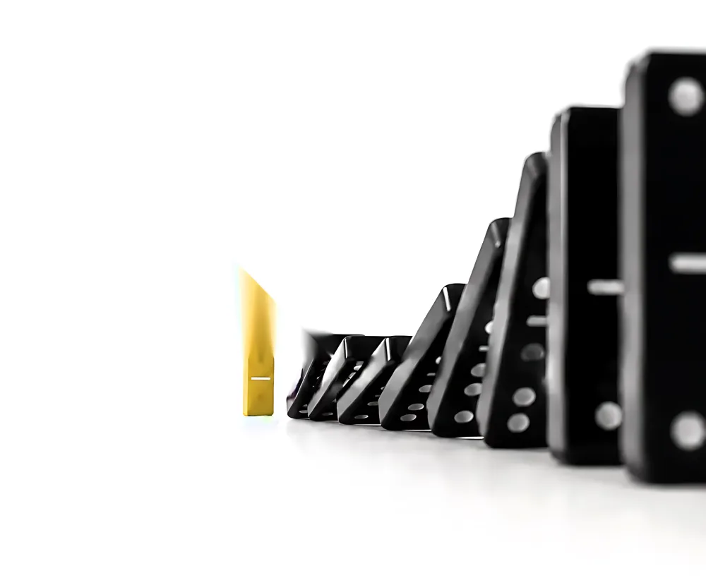 A gold domino holding back a falling line of black dominoes